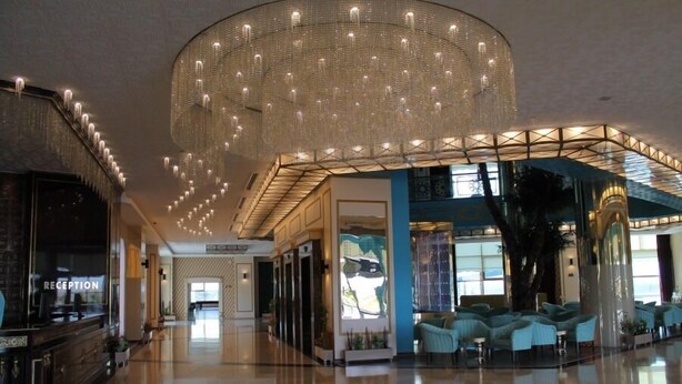 Un hall d’entrée spacieux agrémenté d’un lustre moderne, d’un espace salon et d’un comptoir d’accueil.