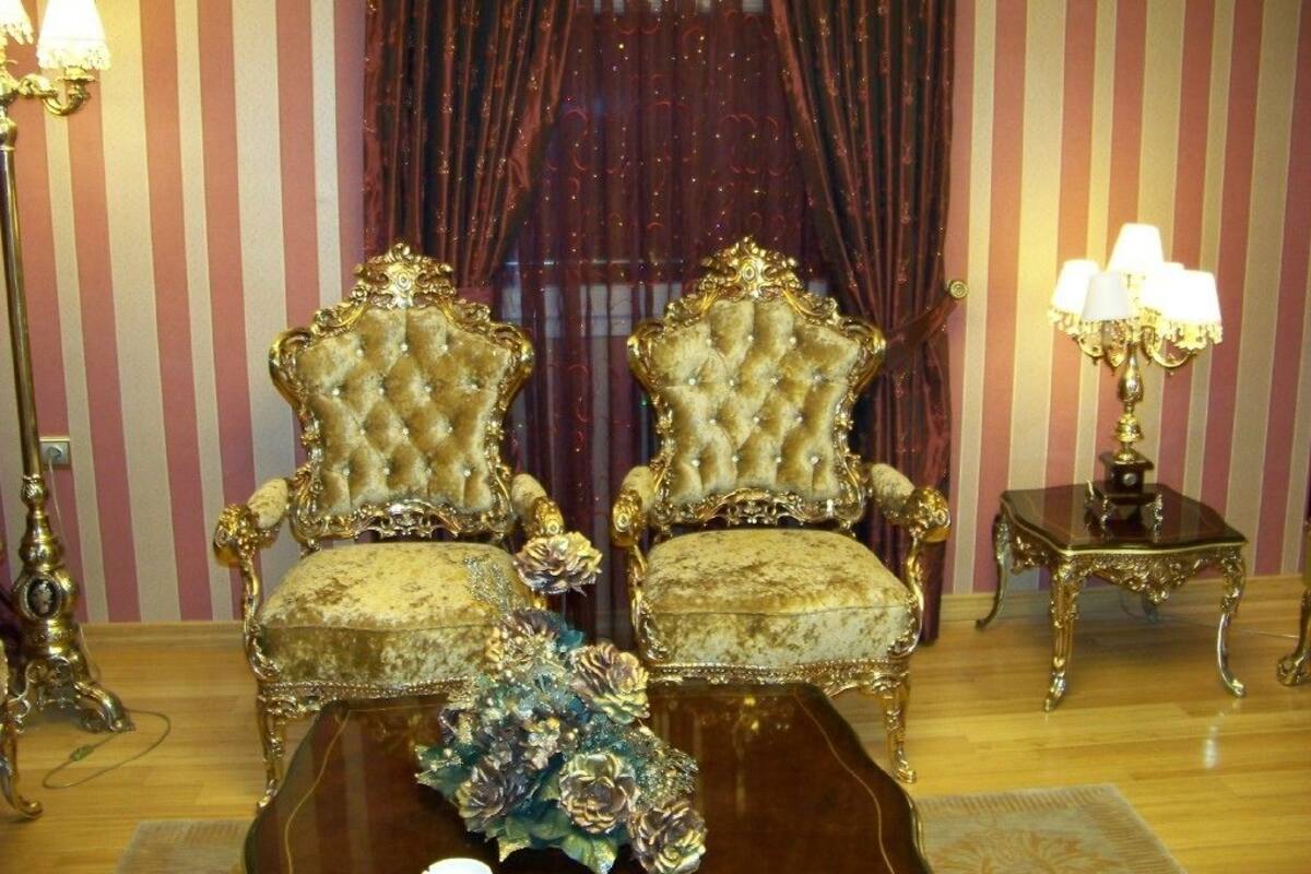 Een kamer met twee sierlijke stoelen, een tafeltje en een lamp.