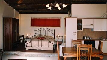 Um quarto com uma cama, uma mesa de madeira e uma área de refeições com cadeiras.