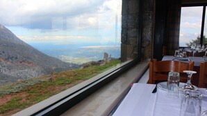 Ein Esstisch mit Blick auf eine gebirgige Landschaft durch ein großes Fenster.