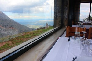 Una mesa de comedor con vistas a un paisaje montañoso a través de un ventanal amplio.