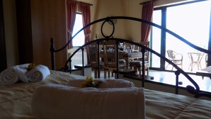 Ein Schlafzimmer mit einem Bett, einem Holzkopfende und Blick auf einen Außenbereich durch große Fenster.