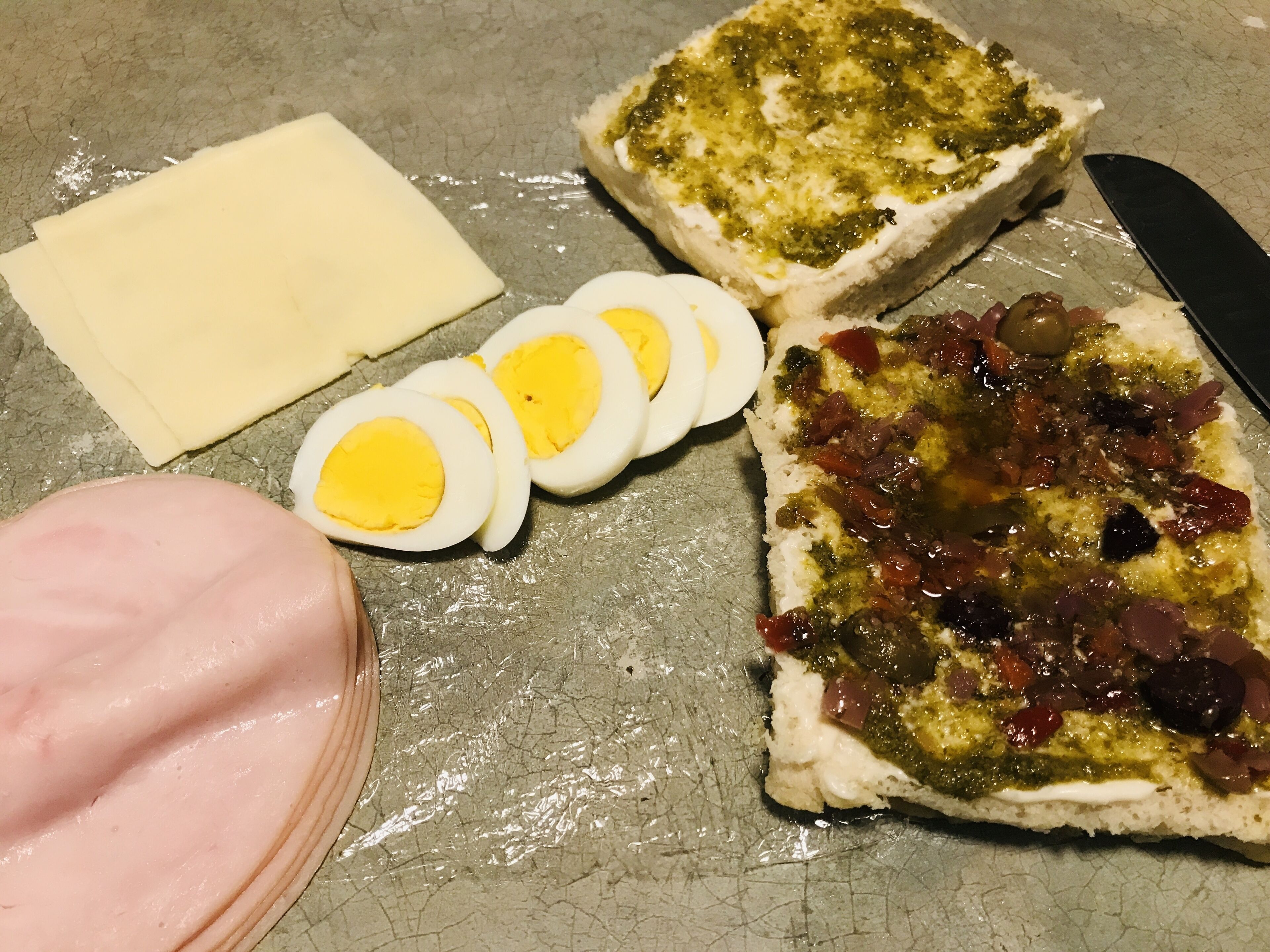 Uma mesa com diversos alimentos, incluindo pão, queijo e ovos fatiados.