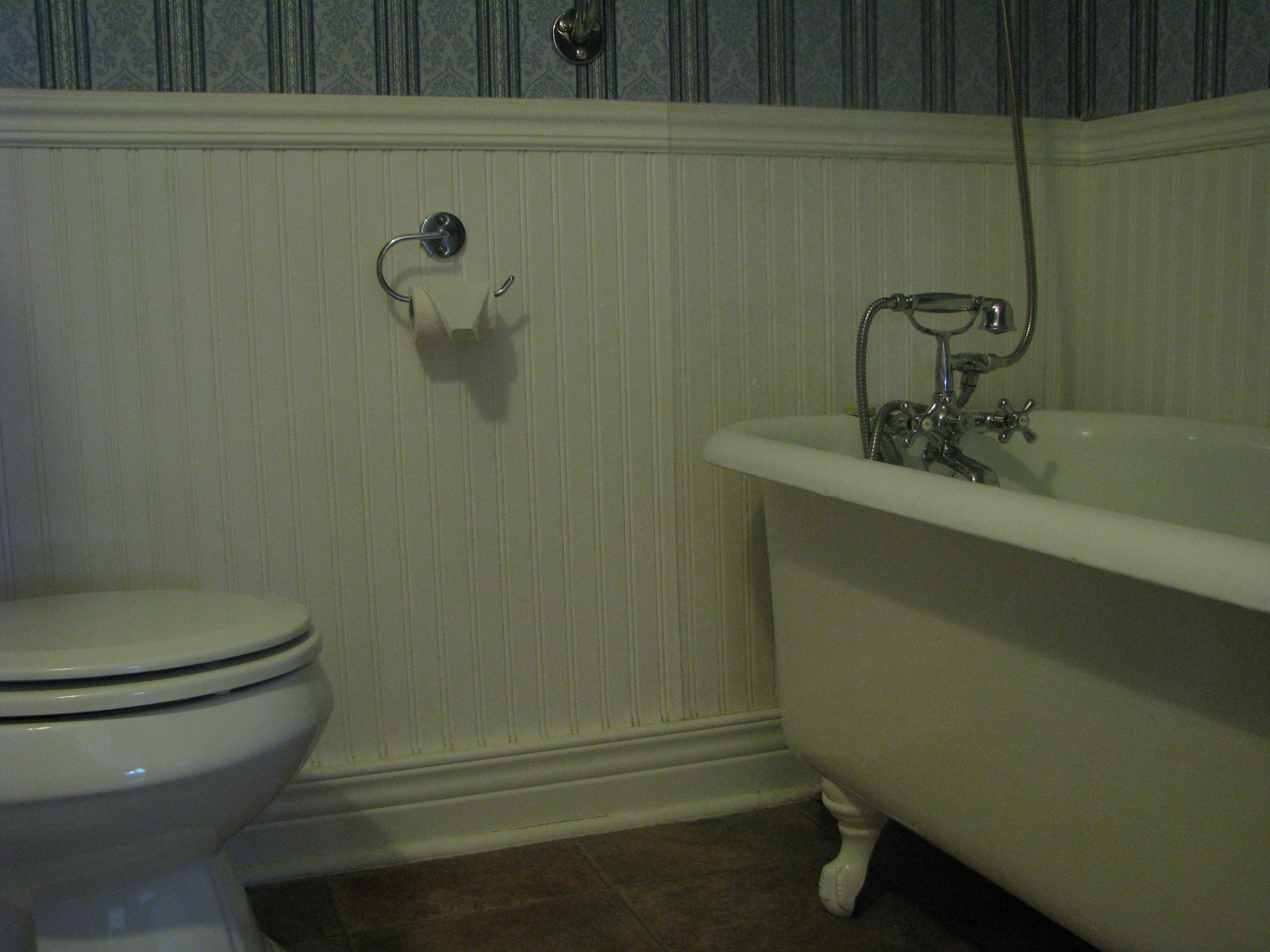 A bathroom with a toilet and an antique-style bathtub.