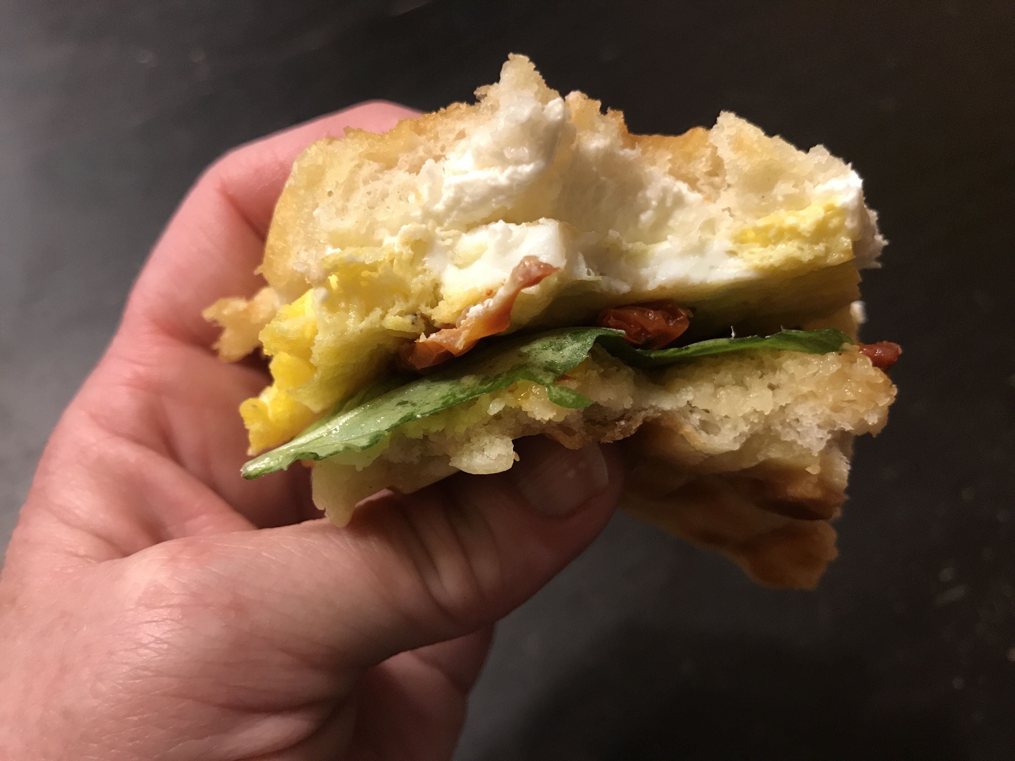 Un sándwich con capas visibles de huevo, tocino y lechuga.