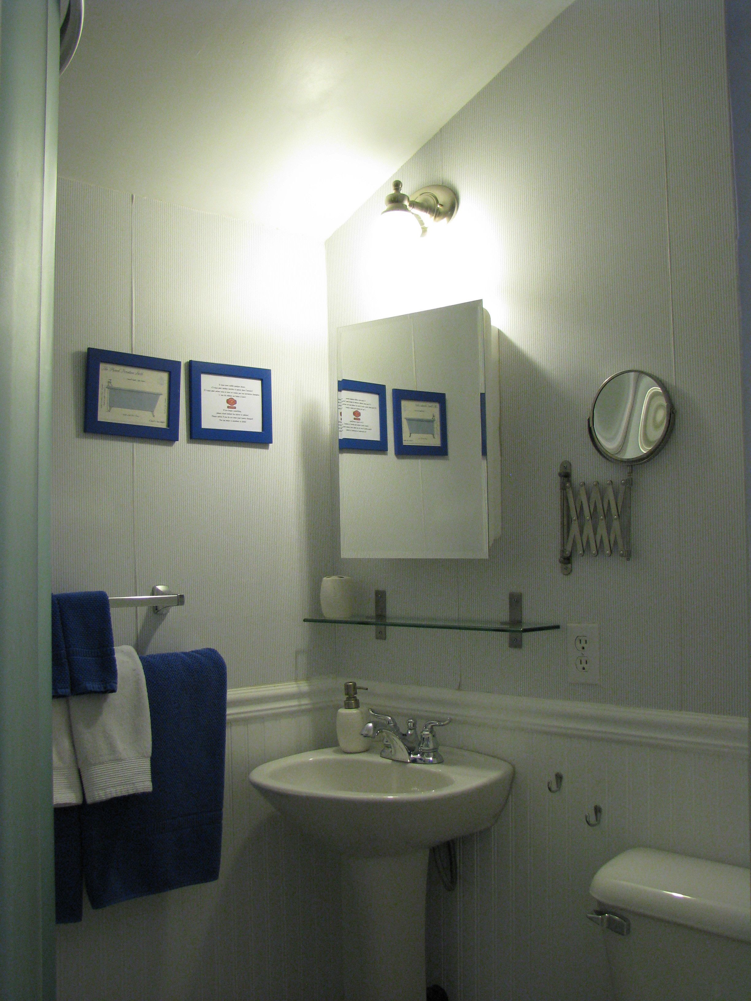 A bathroom with a sink, toilet, and a mirror. There are framed certificates on the wall and a towel rack with towels.