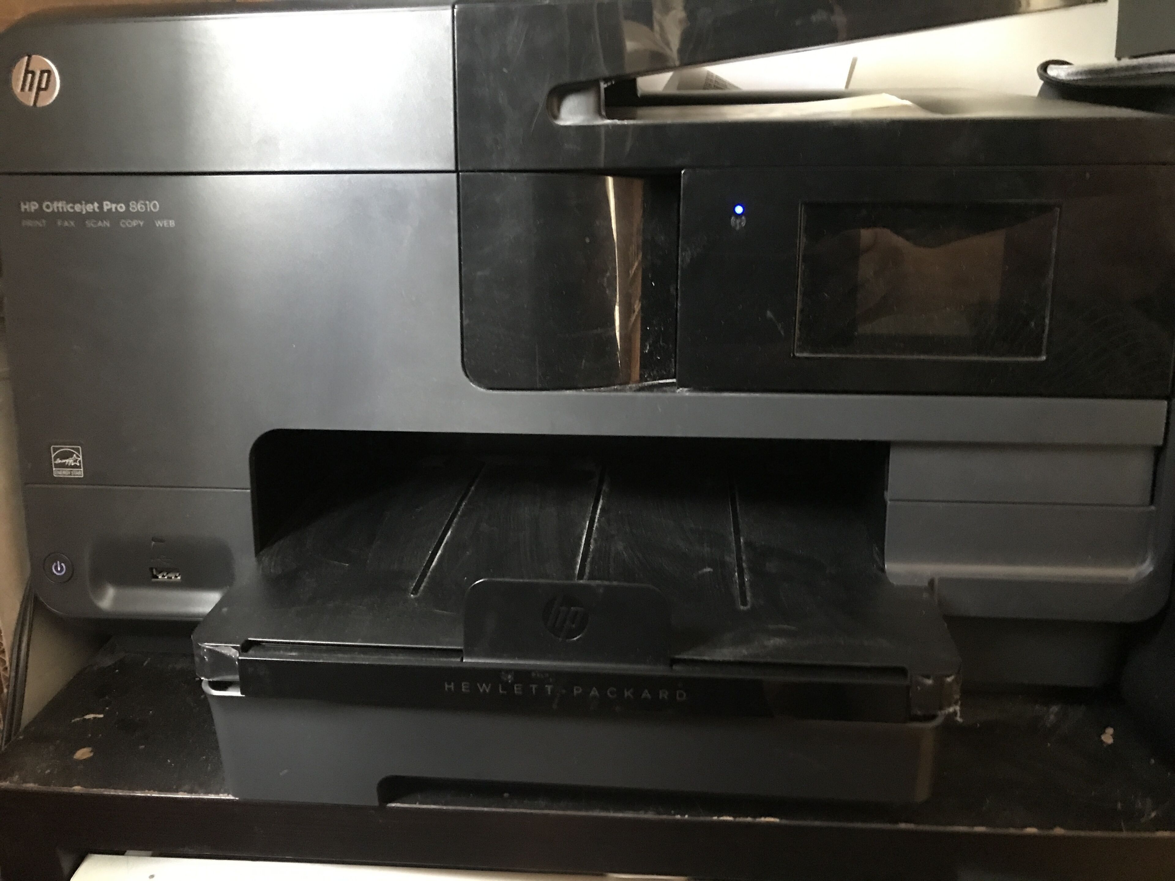 An HP Officejet Pro 8610 printer with a black exterior, a control panel, and a paper output tray.