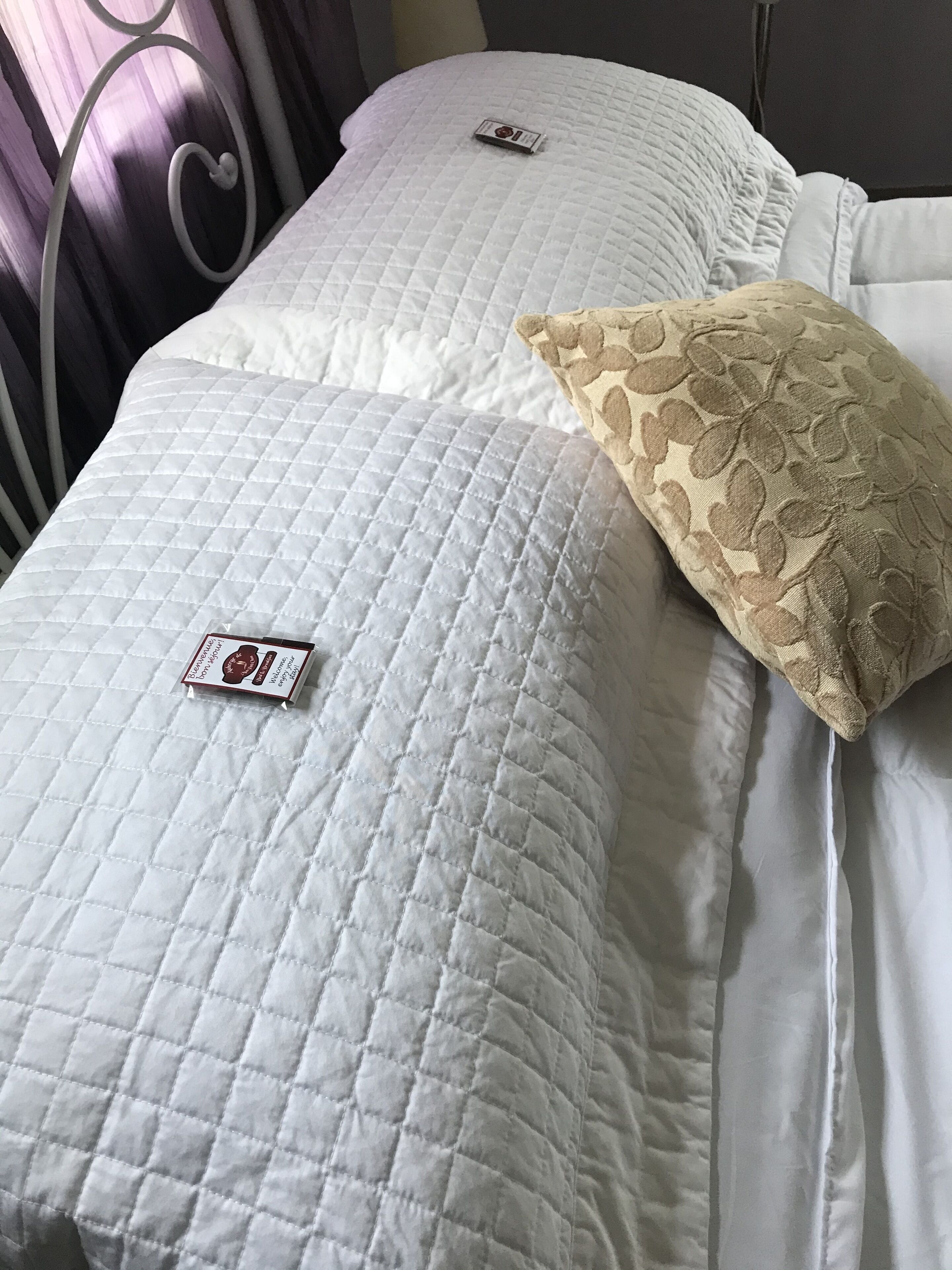 A bed with white bedding and a decorative pillow.