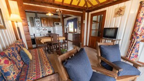 Een knus interieur van een chalet met houten meubels, een eethoek en een televisie.