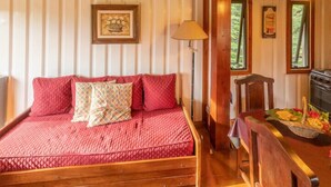 Een gezellige kamer met een houten bed, een lamp en een raam met uitzicht op groen.