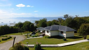 Een chalet met een schuin dak, een veranda en uitzicht op een meer met bootjes.