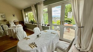 A dining area with a table set for four, white tablecloths, and chairs. - Robin Hill House Heritage B&B (Cobh)