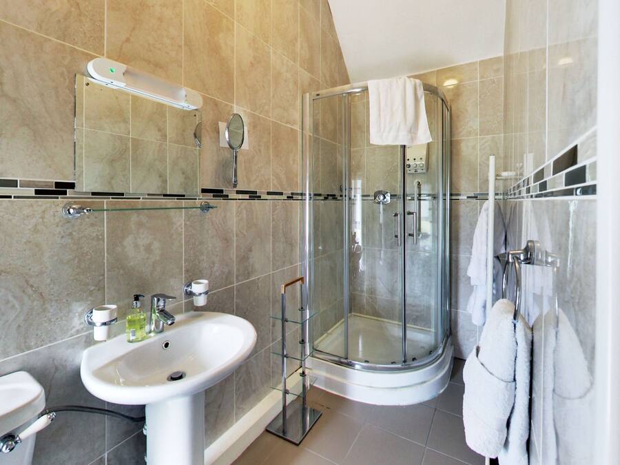 A modern bathroom with a glass-enclosed shower, a sink, and a mirror.