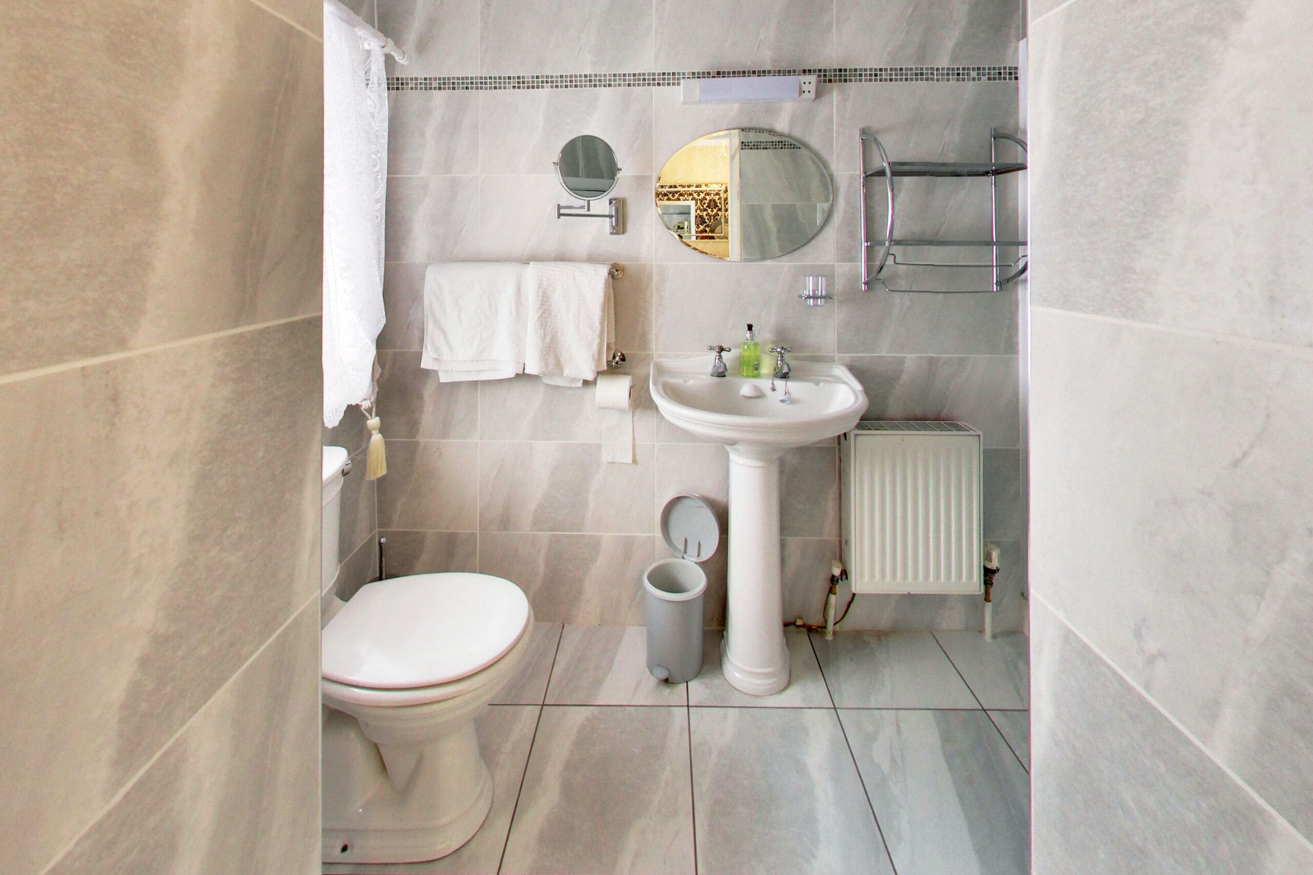 A bathroom with a toilet, sink, mirror, and towel rack.