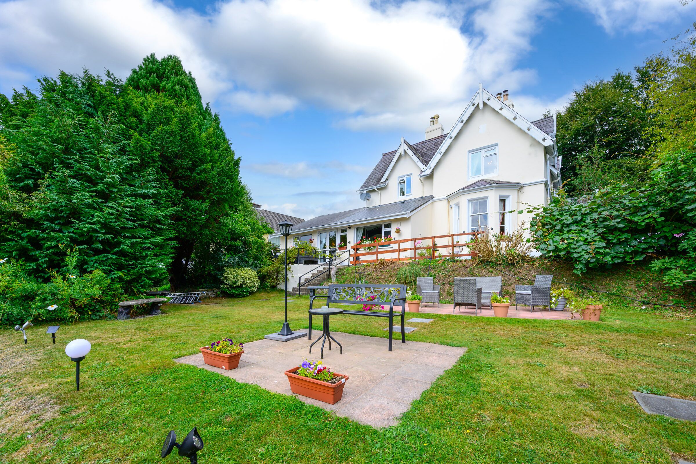 A house with a well-maintained garden, outdoor seating, and a staircase leading to the entrance.