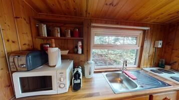A compact kitchen with a microwave, toaster, kettle, and sink.