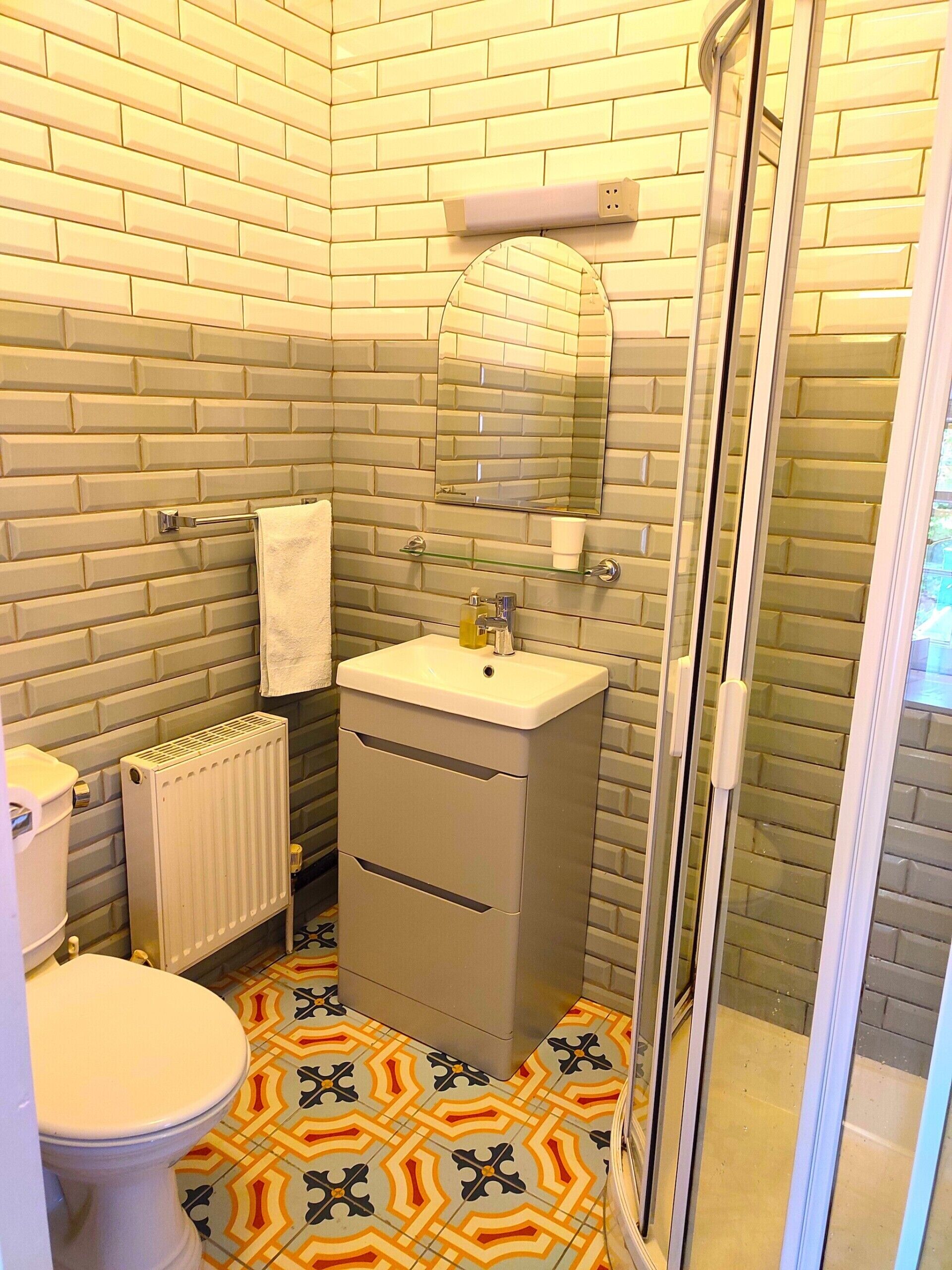 Un baño con inodoro, lavamanos, espejo y zona de ducha.
