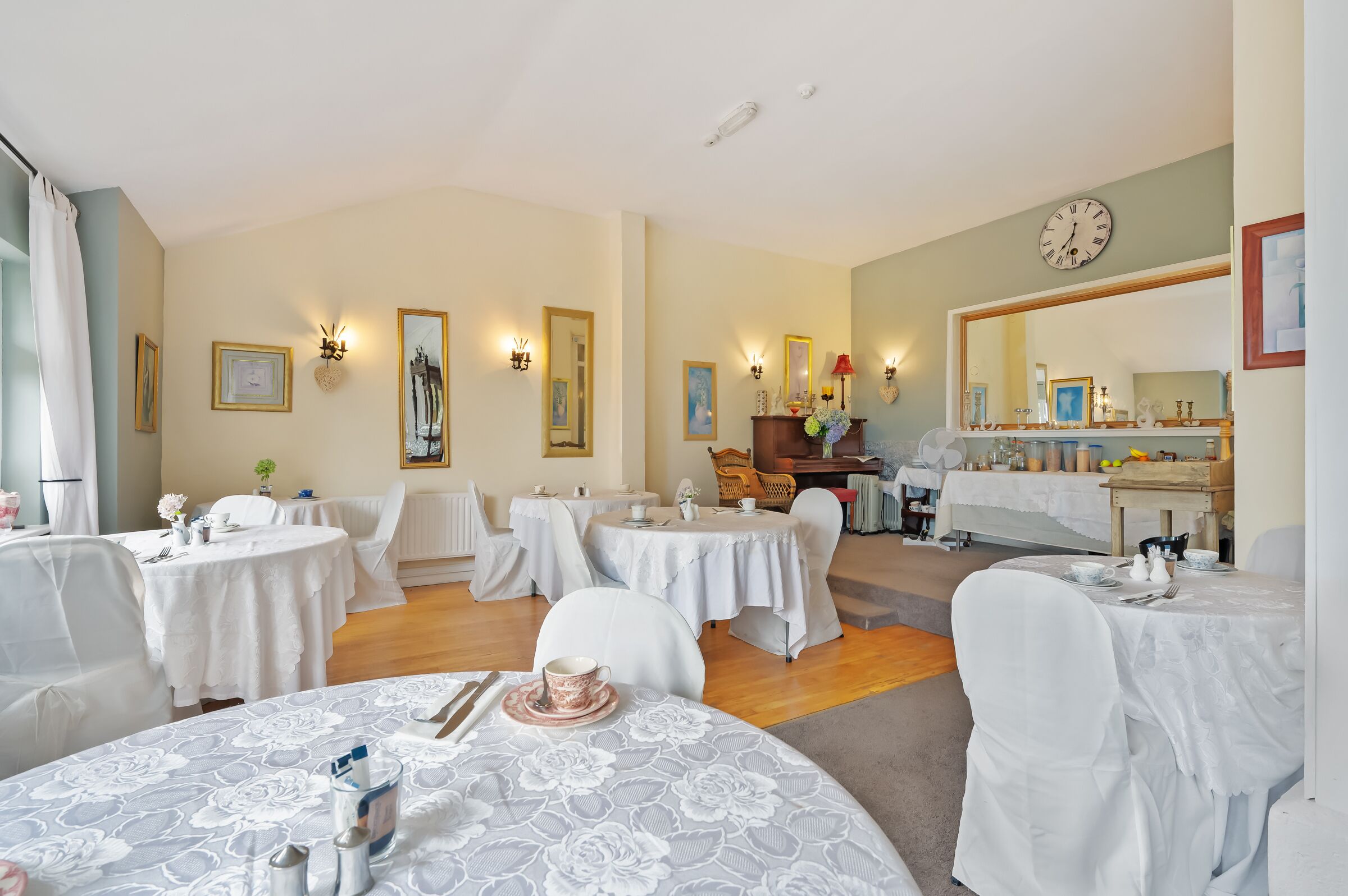 A dining area with round tables, chairs, and a mirror on the wall.