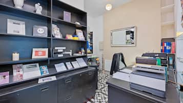 Un mostrador de recepción con piso a cuadros blanco y negro, un espejo en la pared y varias estanterías con premios y certificados.