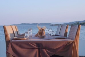 A table set for dining with a view of the sea and distant hills. - Epavlis Resort (Ermionida)