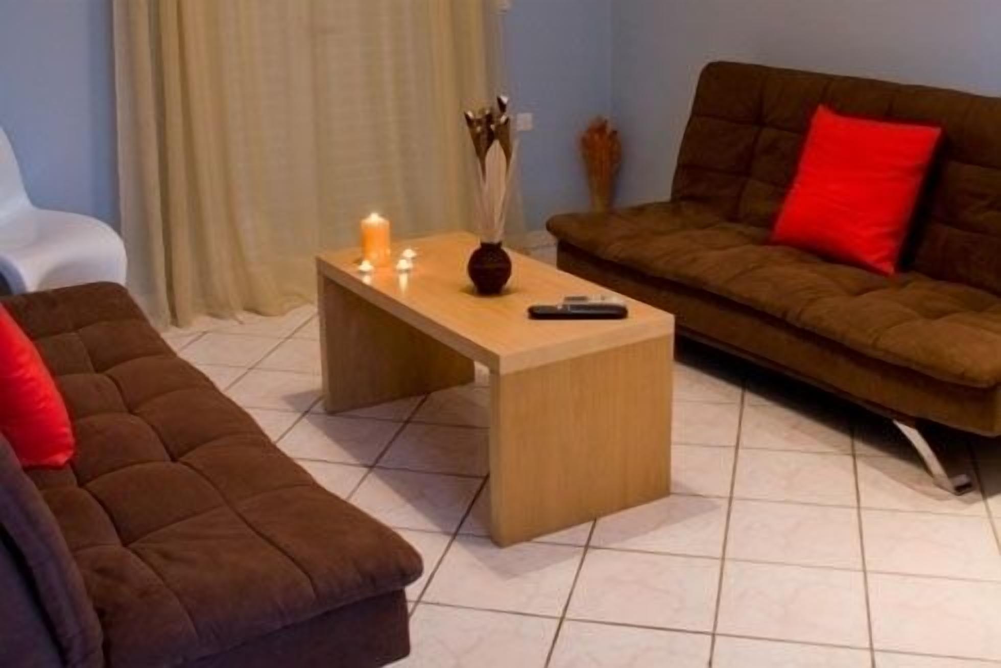 Una sala de estar con un sofá marrón, una mesa de centro de madera y una almohada roja.