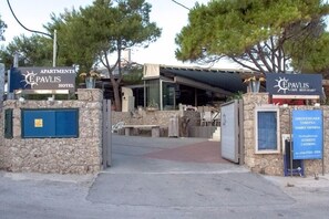 The entrance to the E Pavlis Hotel with a stone facade, a covered outdoor seating area, and signage for the hotel and family tavern. - Epavlis Resort (Ermionida)