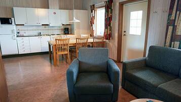 A compact living space with a kitchenette, a dining area, and a seating area with a sofa and armchair.