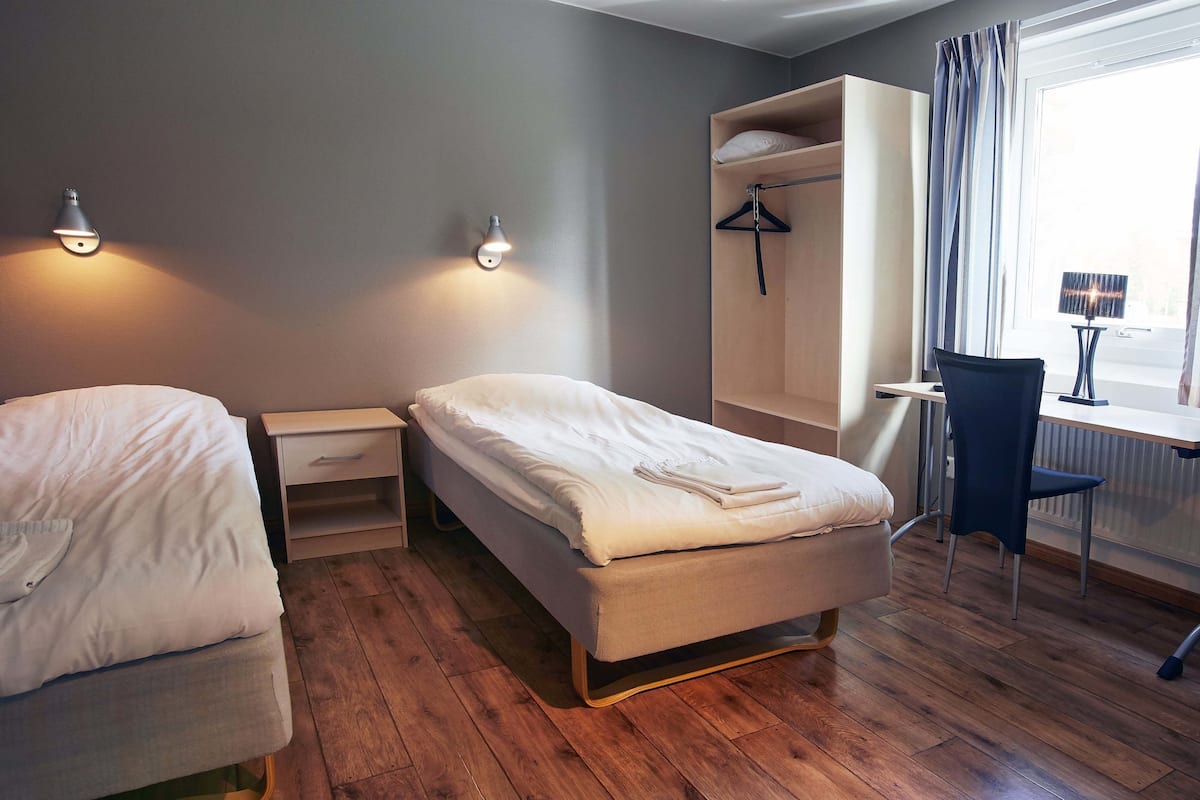 Une chambre avec deux lits, un bureau et une chaise.