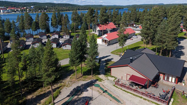 Un complexe hôtelier au bord du lac, comprenant plusieurs chalets, un bâtiment principal avec un toit rouge et une zone aménagée avec un quai.