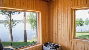 Une cabane aux murs en bois et aux grandes fenêtres donnant sur un lac.