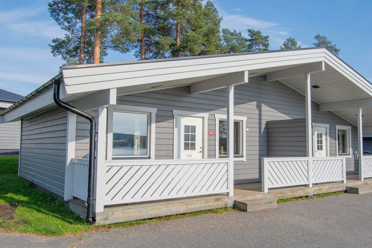 Une maison mobile de plain-pied dotée d’une véranda, de grandes fenêtres et d’un garage.