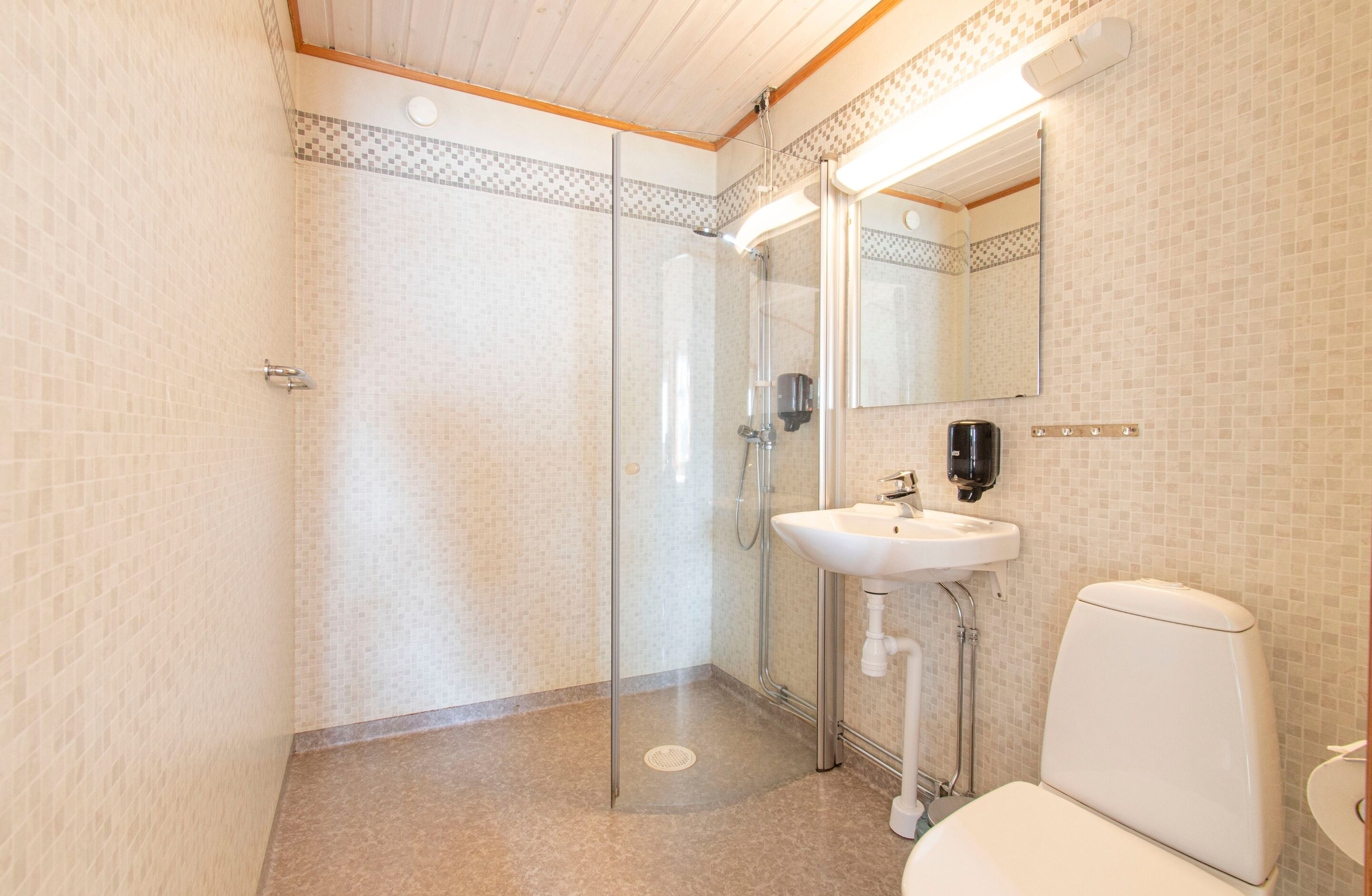 Un baño con cabina de ducha de vidrio, lavamanos e inodoro.