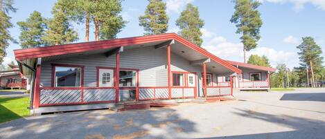 A building with a red and white exterior, multiple windows, and a covered porch area.