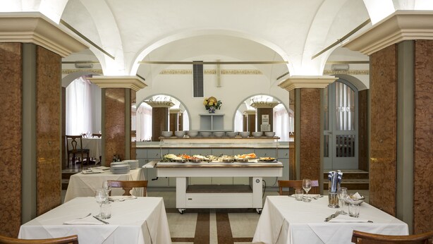 A dining area with marble walls, white ceiling arches, and a buffet table. - Hotel Villa delle Fonti (Riolo Terme)