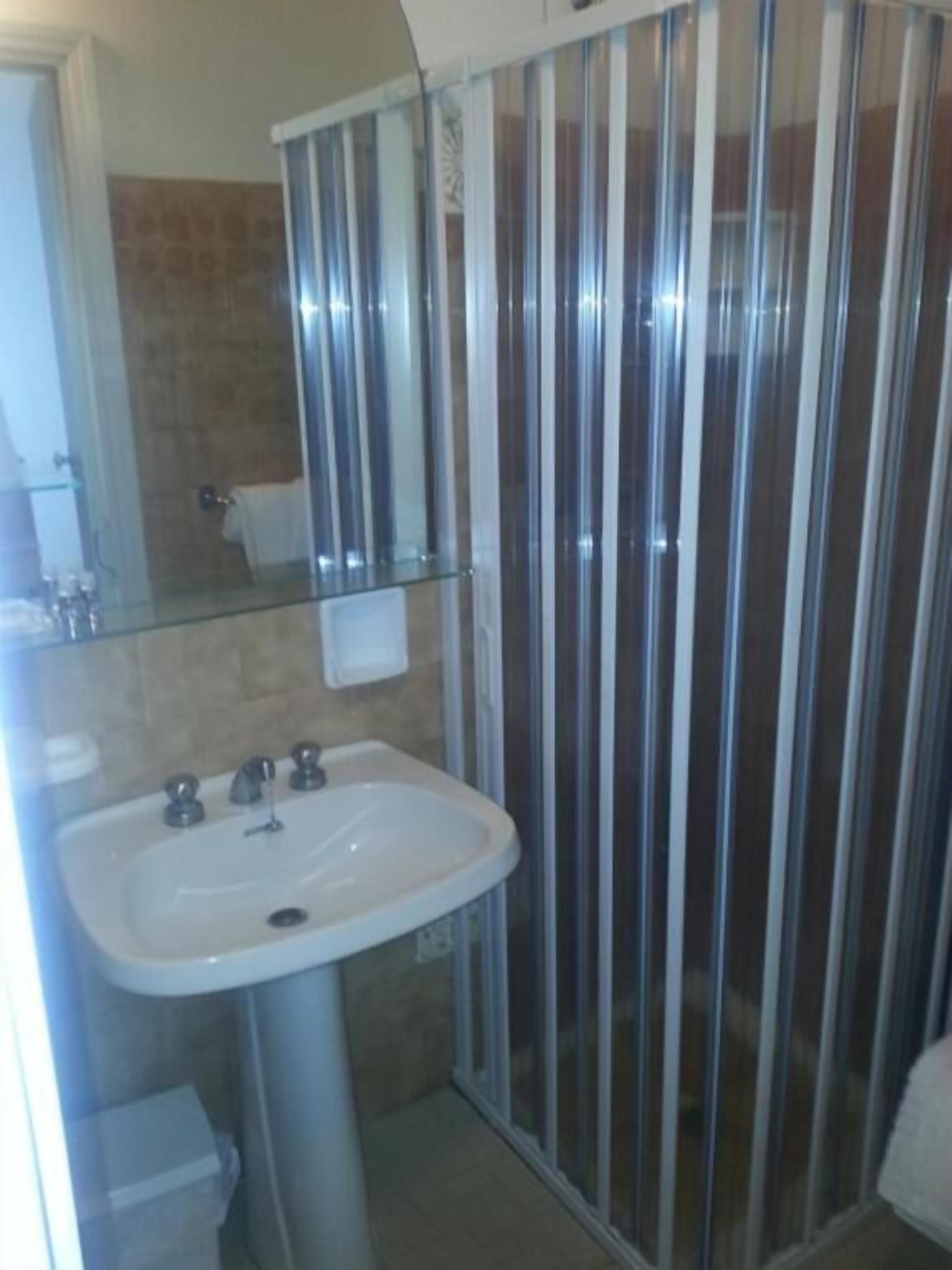 Une salle de bain avec une douche à parois de verre, un lavabo et un miroir.
