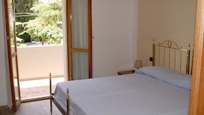A bedroom with a bed, a nightstand, a lamp, and a view of the outside. - Hotel Villa delle Fonti (Riolo Terme)
