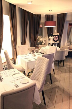 A dining area with white tablecloths, neatly set tables, and a mannequin in the background. - Old Street Kostroma (Kostroma)