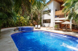 Una piscina al aire libre, sombrillas, sillones reclinables de piscina