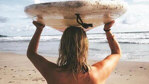 A person carrying a surfboard on their head on a beach. - Atrapasuenos Dreamcatcher Hotel (Cóbano)