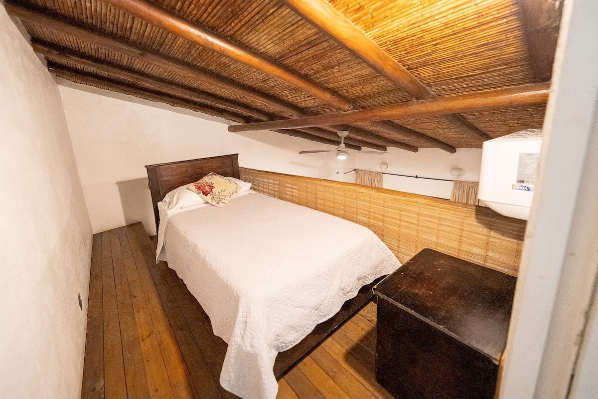 A small, single-bed room with a wooden ceiling and a ceiling fan.
