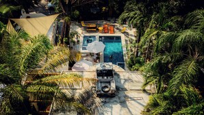 An aerial view of a resort with a swimming pool, lounge chairs, and palm trees. - Atrapasuenos Dreamcatcher Hotel (Cóbano)