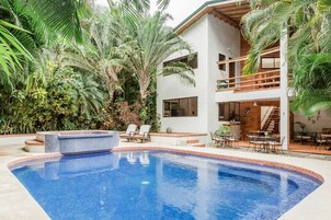 Una piscina al aire libre, sombrillas, sillones reclinables de piscina