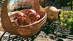 A wicker basket filled with pomegranates on a metal table outdoors.