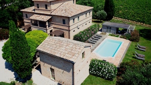 A large, multi-story brick building with a swimming pool and outdoor seating.