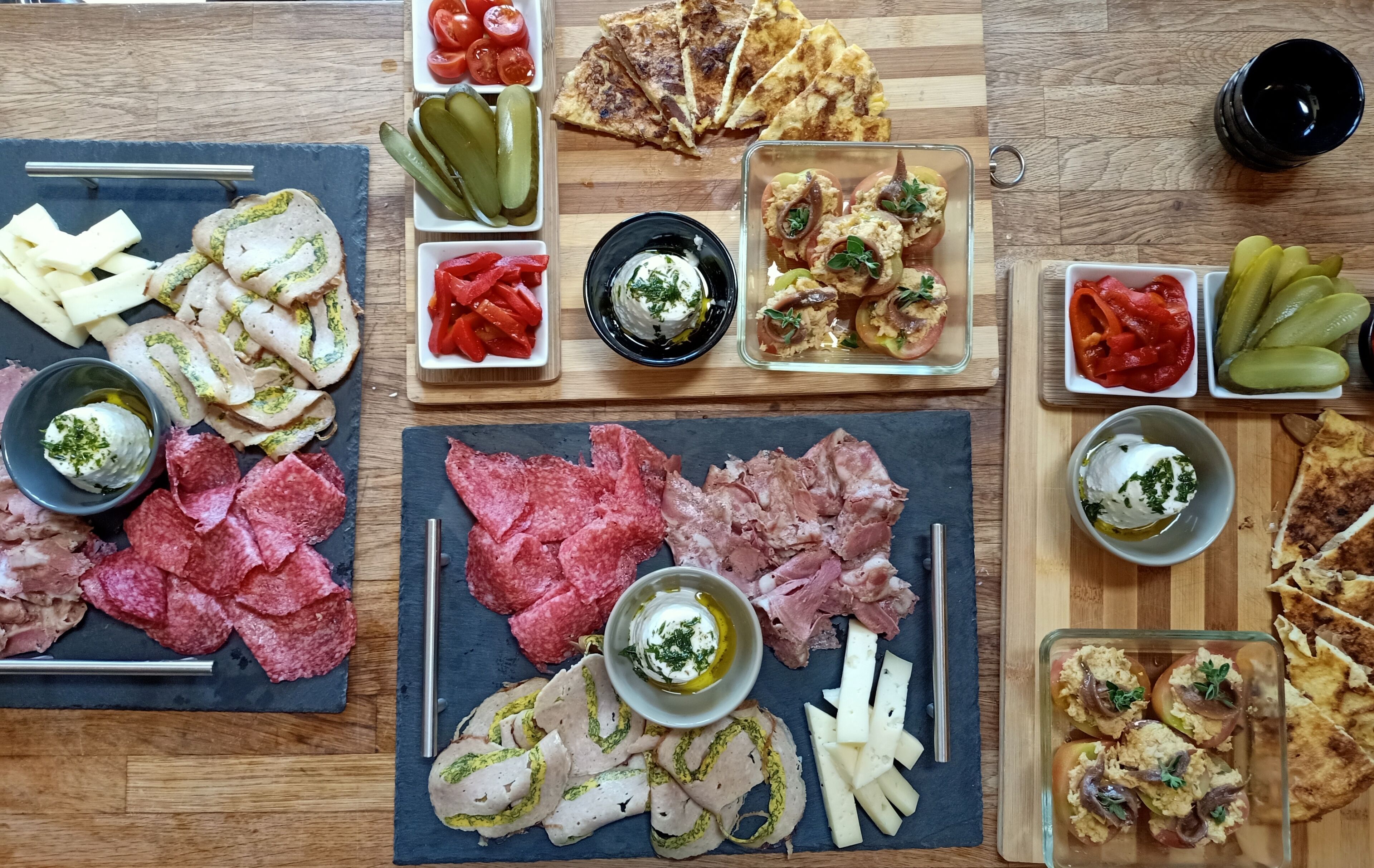 A variety of food items including meats, cheeses, and vegetables arranged on a wooden table.