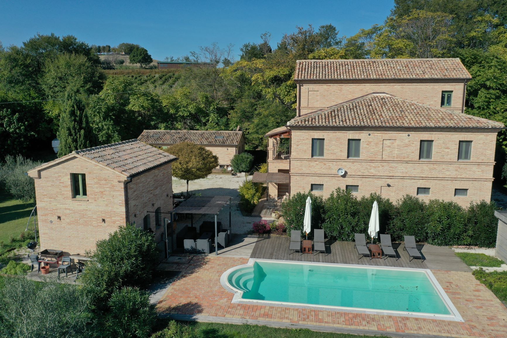 Una gran vila amb piscina, mobiliari d'exterior i jardí.