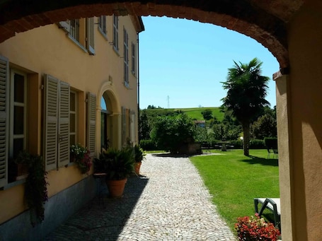 An arched entrance to a building with a cobblestone pathway leading to a grassy area.
