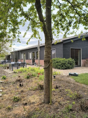 A modern building with a patio area, outdoor seating, and a well-maintained garden. - Studio Verhuur Jamzes (Hoogerheide)