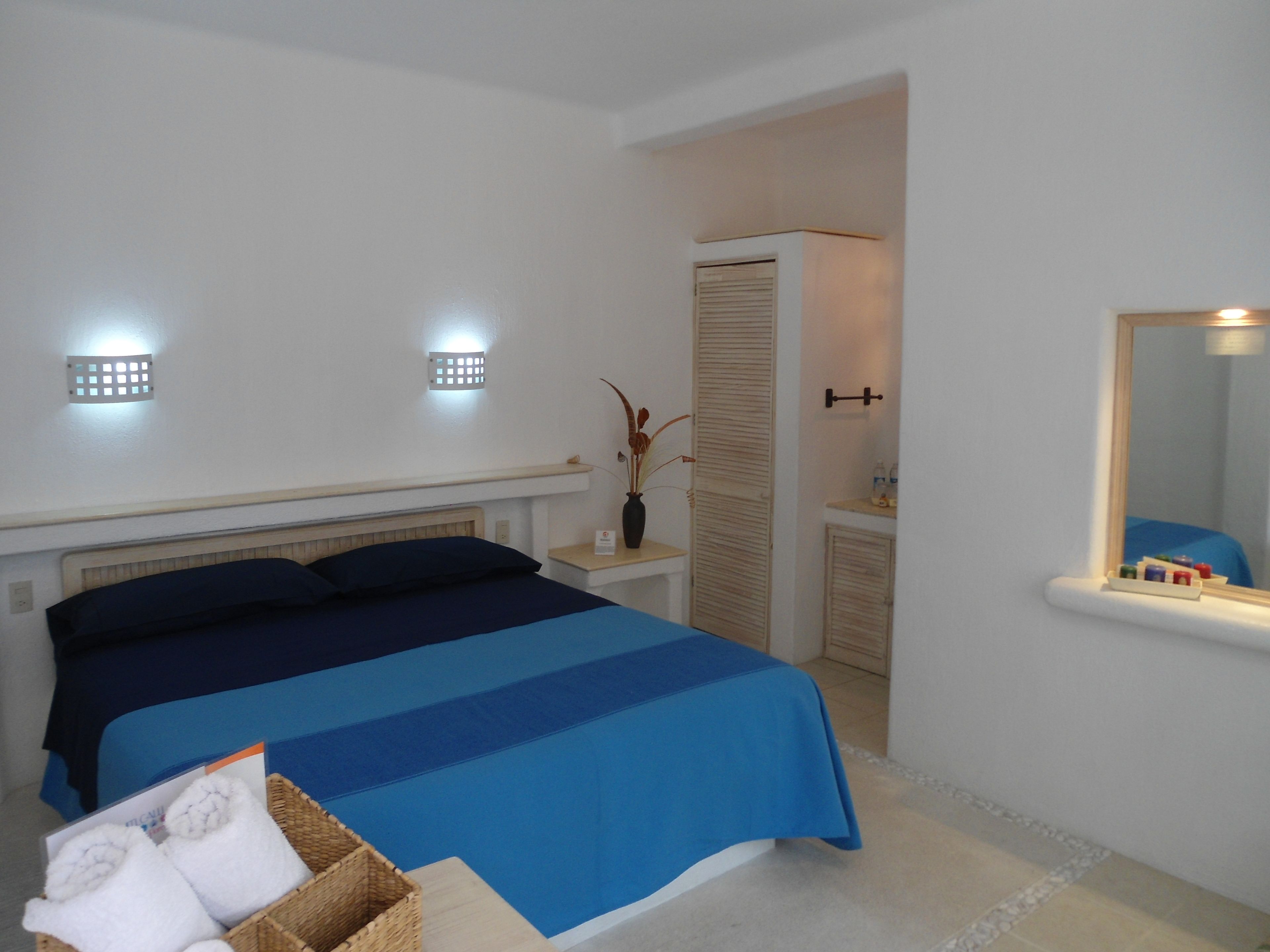 A bedroom with a bed, bedside tables, a mirror, and a nightstand.