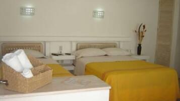 A hotel room with a bed, bedside tables, a lamp, a basket, and a vase with dried flowers.